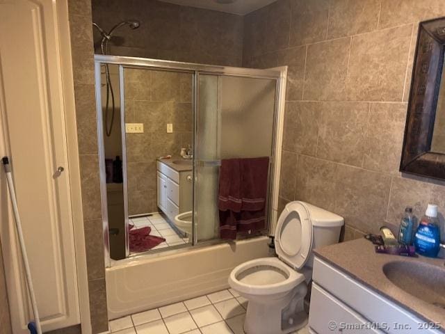 bathroom with enclosed tub / shower combo, toilet, tile walls, and tile patterned flooring