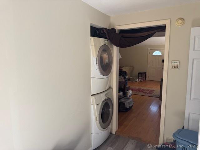 washroom with laundry area, wood finished floors, and stacked washer and clothes dryer