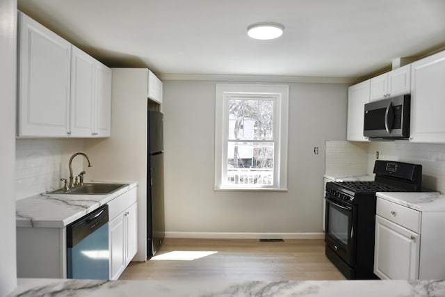 kitchen with stainless steel microwave, dishwashing machine, freestanding refrigerator, black range with gas cooktop, and a sink