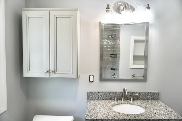 full bath with toilet, vanity, and a tile shower