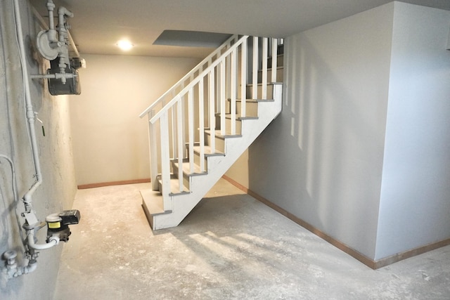 staircase featuring baseboards and concrete flooring