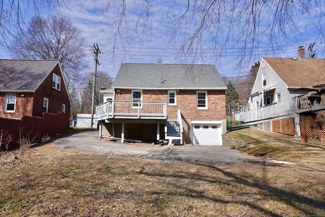 back of house with stairs, a garage, a deck, aphalt driveway, and brick siding