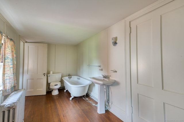 673 Spring St, Manchester, CT 06040 - bathroom with radiator heating unit, a decorative wall, a soaking tub, wood finished floors, and toilet