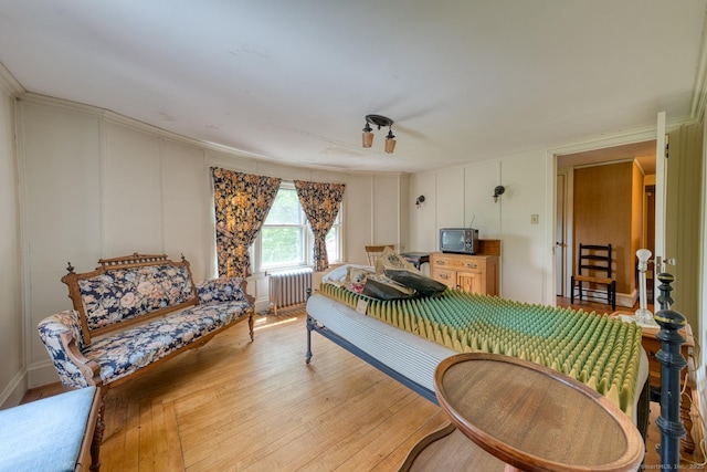 673 Spring St, Manchester, CT 06040 - bedroom featuring radiator heating unit, light wood-type flooring, and a decorative wall