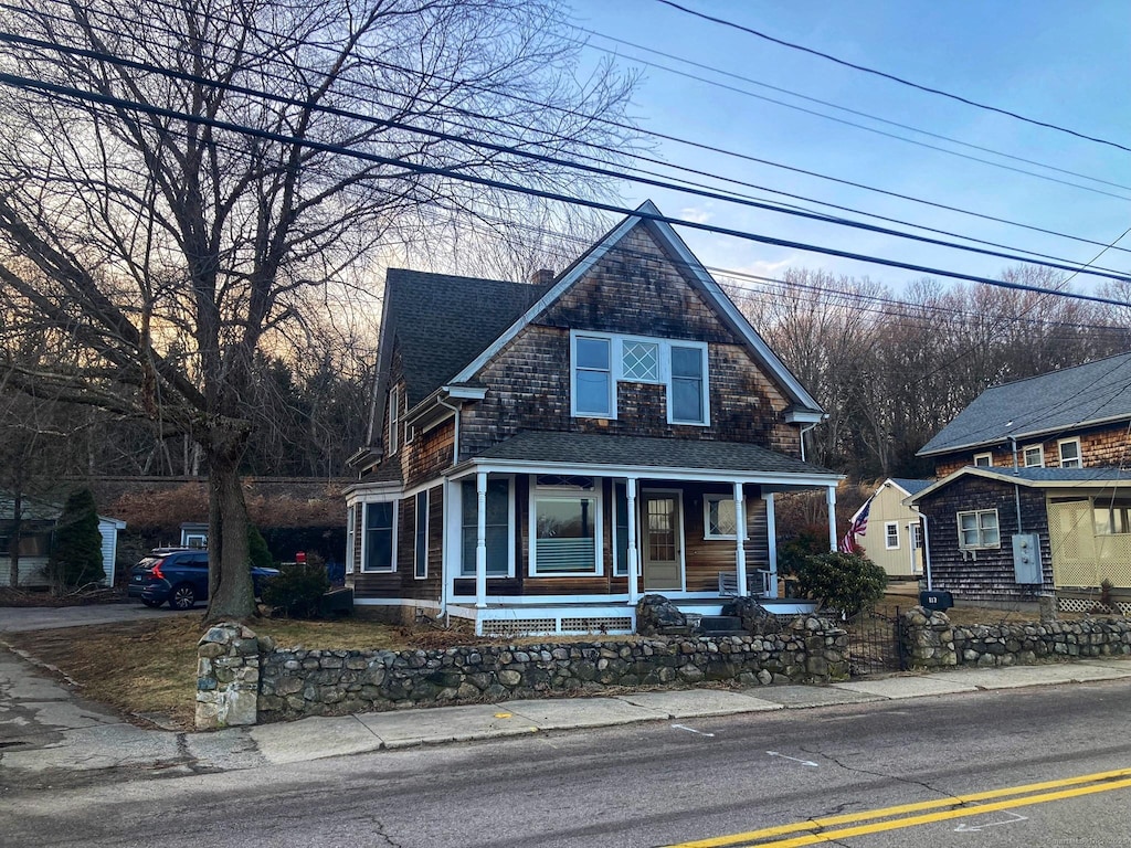 view of front of house with a fenced front yard, a porch, a chimney, and roof with shingles