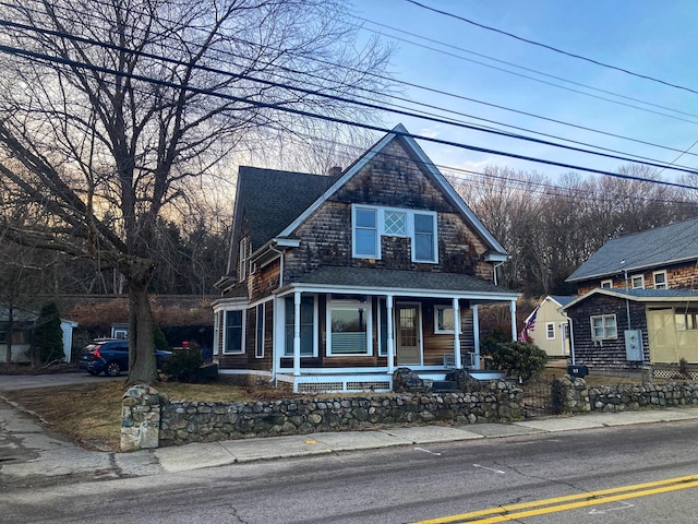 view of front of house with a fenced front yard, a porch, a chimney, and roof with shingles