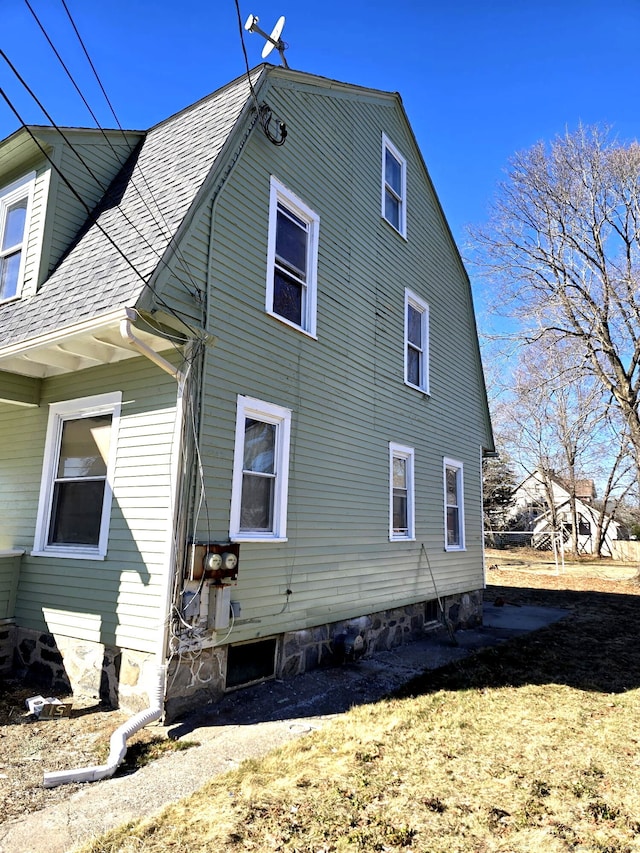 view of home's exterior featuring a gambrel roof and a shingled roof