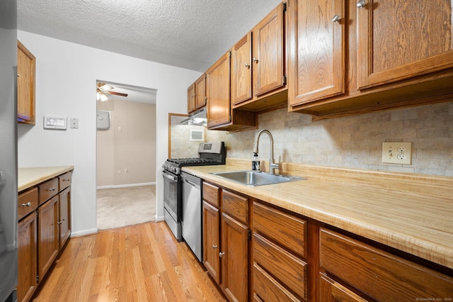 kitchen with a sink, stainless steel appliances, brown cabinets, and light countertops