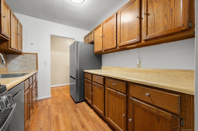 kitchen featuring brown cabinets, light countertops, light wood-style floors, and a sink