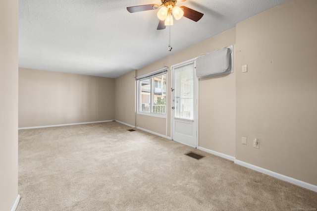 empty room with visible vents, a ceiling fan, a textured ceiling, carpet, and baseboards