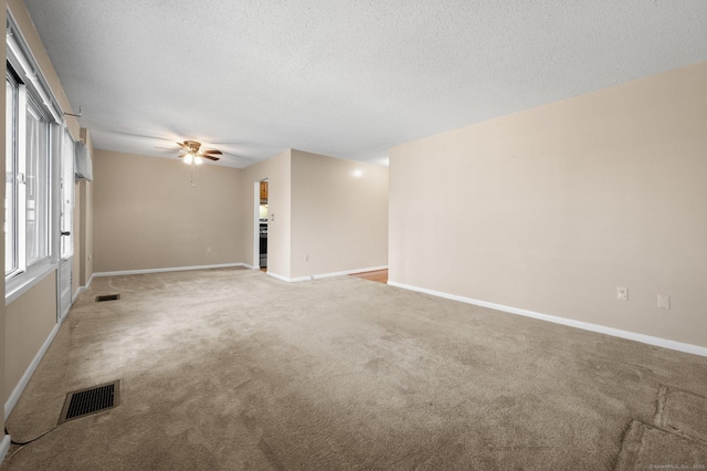 spare room with visible vents, carpet flooring, a textured ceiling, and baseboards