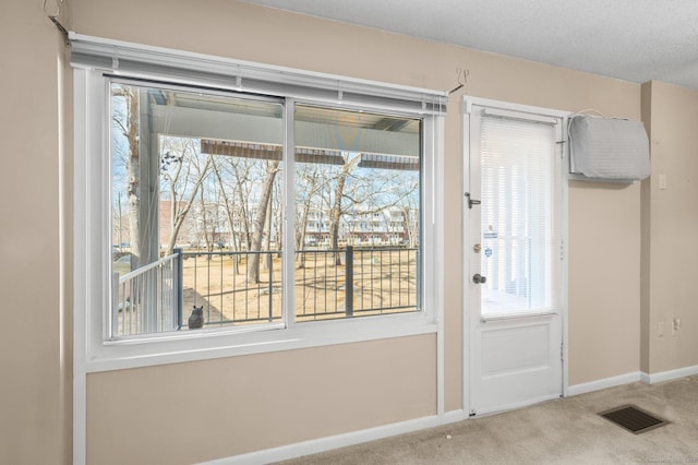 doorway to outside with carpet, visible vents, and baseboards