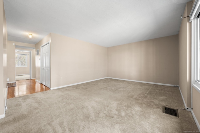 carpeted empty room with visible vents and baseboards