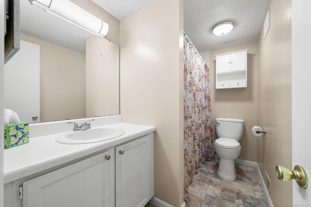 bathroom featuring vanity, baseboards, stone finish floor, a textured ceiling, and toilet