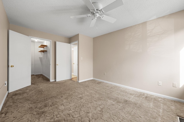 unfurnished bedroom with a ceiling fan, a textured ceiling, carpet flooring, baseboards, and a spacious closet