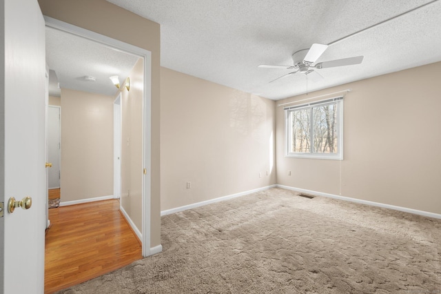 carpeted spare room featuring visible vents, baseboards, a textured ceiling, and a ceiling fan