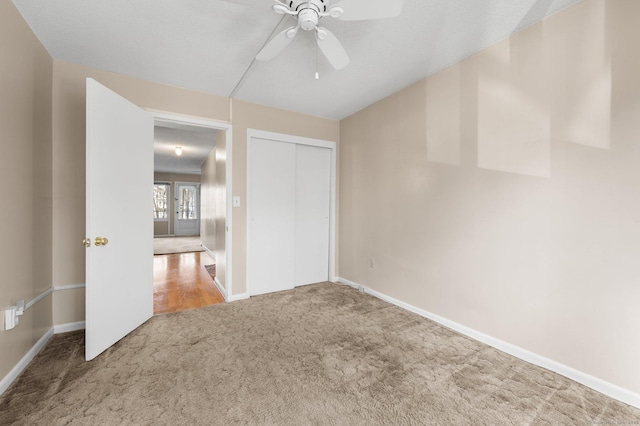 unfurnished bedroom with a ceiling fan, carpet, a closet, and baseboards