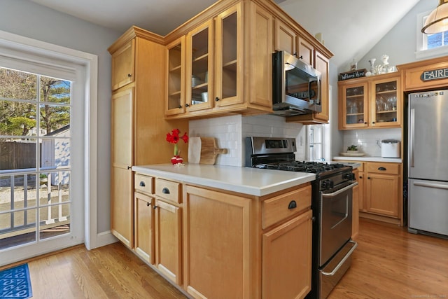 kitchen featuring decorative backsplash, stainless steel appliances, light countertops, and light wood-style floors