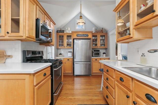 kitchen featuring stainless steel appliances, light wood-style floors, light countertops, glass insert cabinets, and lofted ceiling