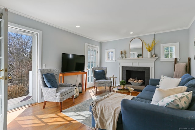 living room featuring wood finished floors, recessed lighting, french doors, a fireplace, and crown molding