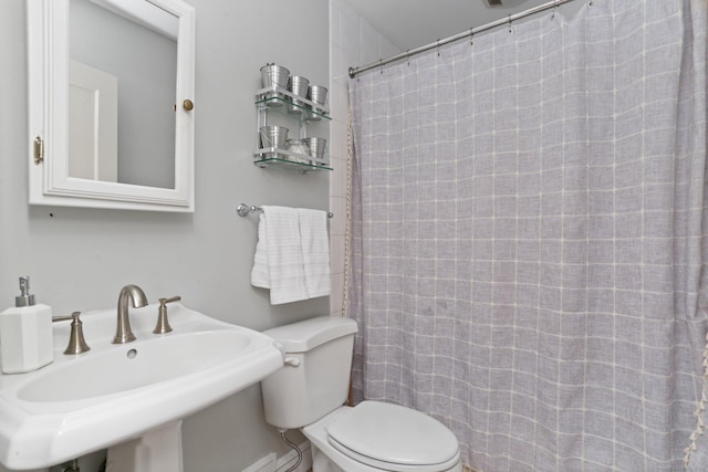 bathroom featuring toilet, a shower with curtain, and a sink