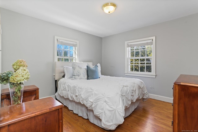 bedroom featuring multiple windows, wood finished floors, and baseboards