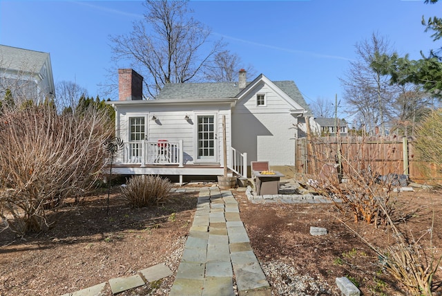 back of property with fence, a shingled roof, a chimney, a deck, and brick siding