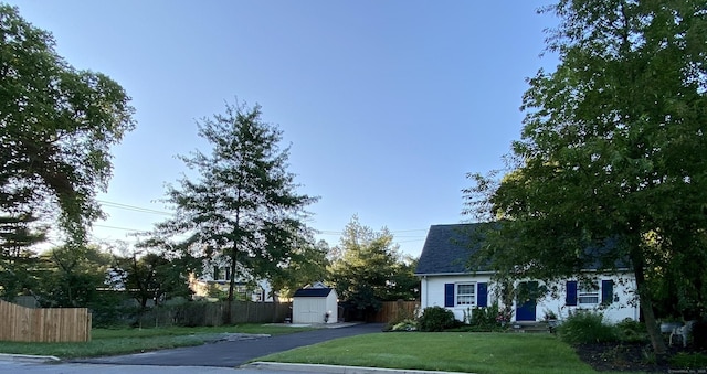 view of front of property featuring an outdoor structure, a storage unit, fence, and a front yard