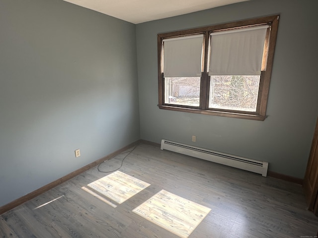 unfurnished room featuring wood finished floors, baseboards, and a baseboard radiator