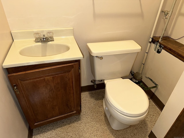 bathroom featuring vanity, toilet, baseboards, and speckled floor