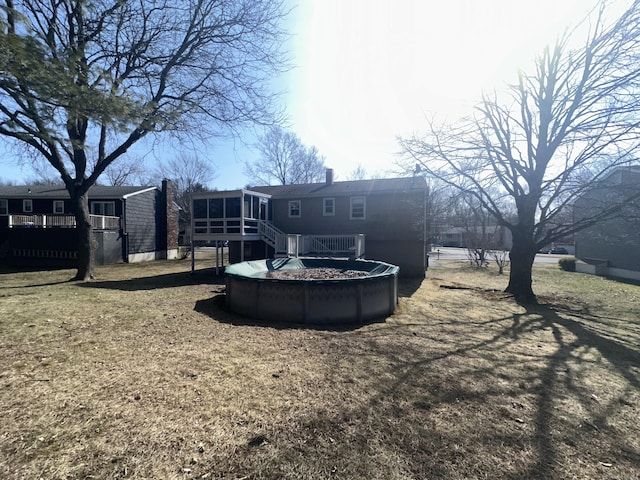 rear view of property featuring a covered pool, a chimney, a deck, and a sunroom