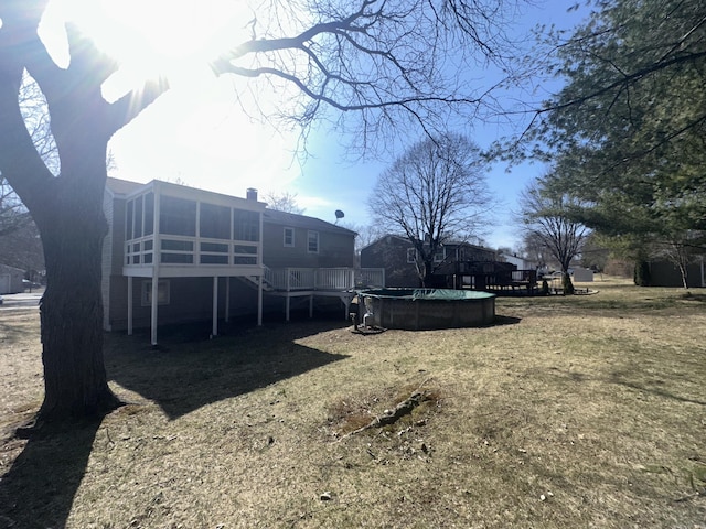 view of yard with a covered pool, a wooden deck, and a sunroom