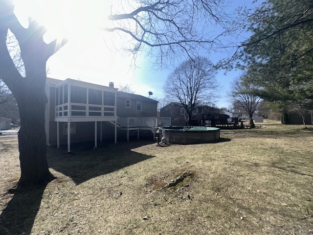 view of yard with a covered pool, a deck, and a sunroom