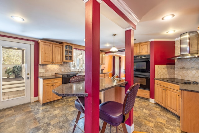 kitchen featuring black appliances, ornamental molding, stone finish floor, wall chimney range hood, and glass insert cabinets