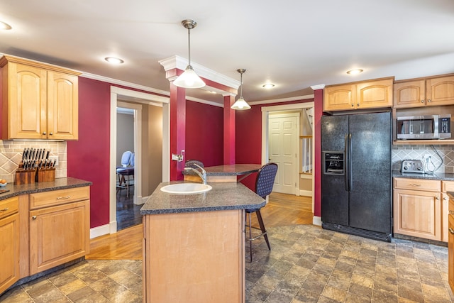 kitchen featuring baseboards, a breakfast bar, a sink, black fridge with ice dispenser, and stainless steel microwave