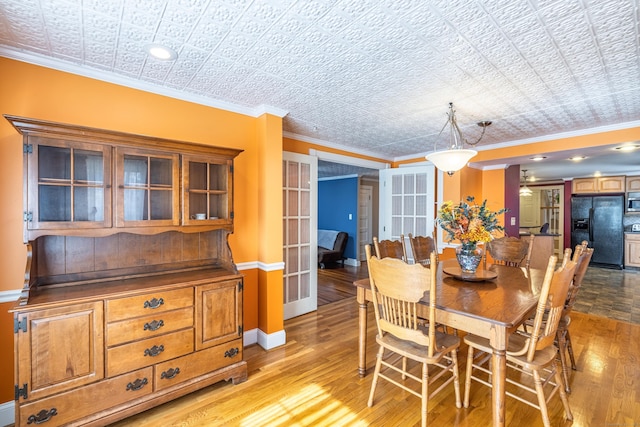 dining room with baseboards, ornamental molding, light wood-style flooring, french doors, and an ornate ceiling