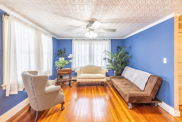 living area featuring ceiling fan, hardwood / wood-style flooring, baseboards, and ornamental molding