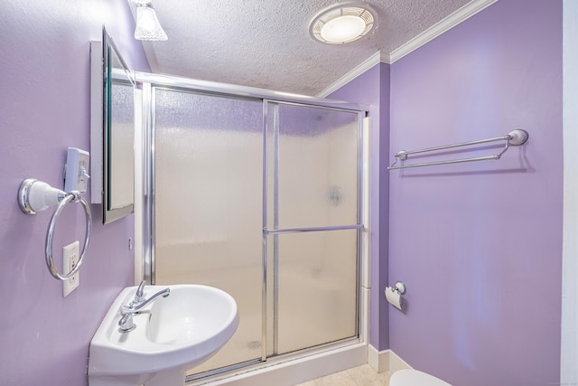 full bathroom featuring ornamental molding, tile patterned flooring, a shower stall, a sink, and a textured ceiling