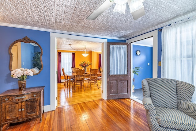 interior space featuring an ornate ceiling, wood-type flooring, ceiling fan, and ornamental molding