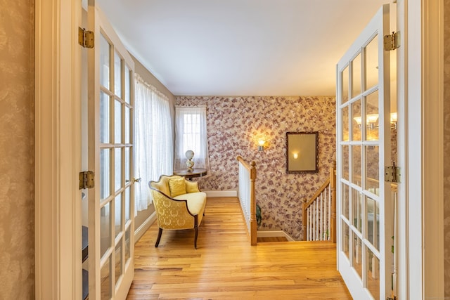 sitting room featuring french doors, baseboards, wood finished floors, and wallpapered walls