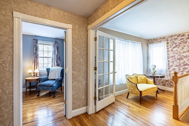 living area with baseboards, hardwood / wood-style floors, and wallpapered walls