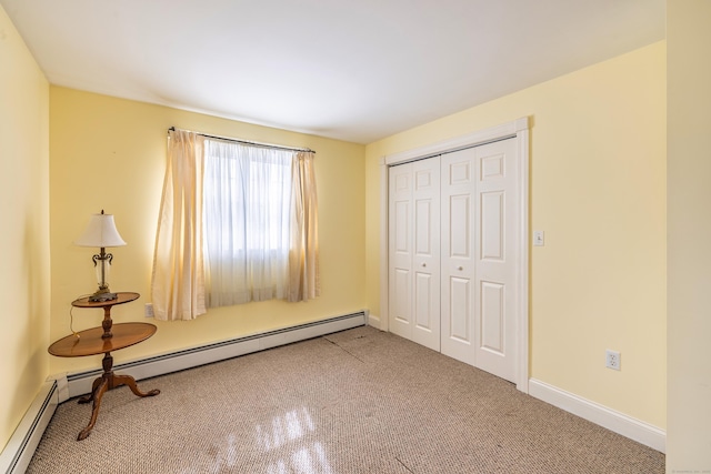 unfurnished bedroom featuring a closet, carpet flooring, a baseboard heating unit, and baseboards