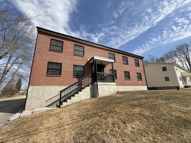 rear view of house featuring a yard and brick siding