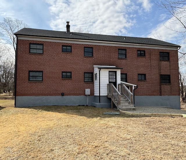 back of property featuring brick siding and a lawn