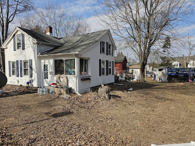 view of side of home featuring a chimney and a shingled roof