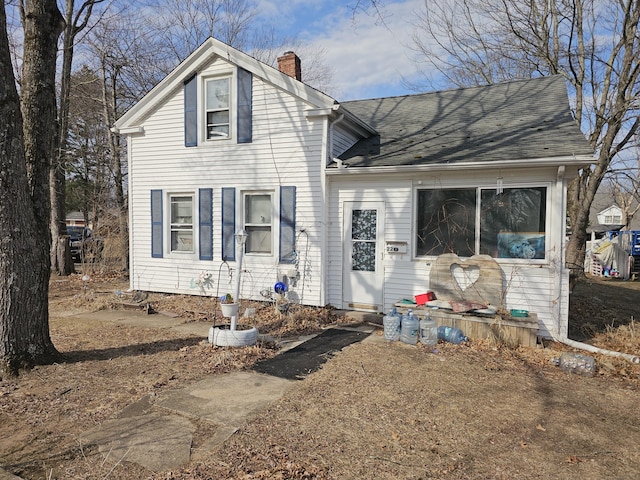 view of front facade featuring a chimney and roof with shingles