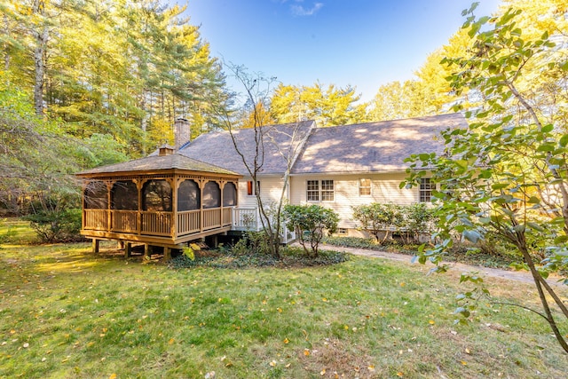 back of property with a gazebo, a lawn, and a chimney