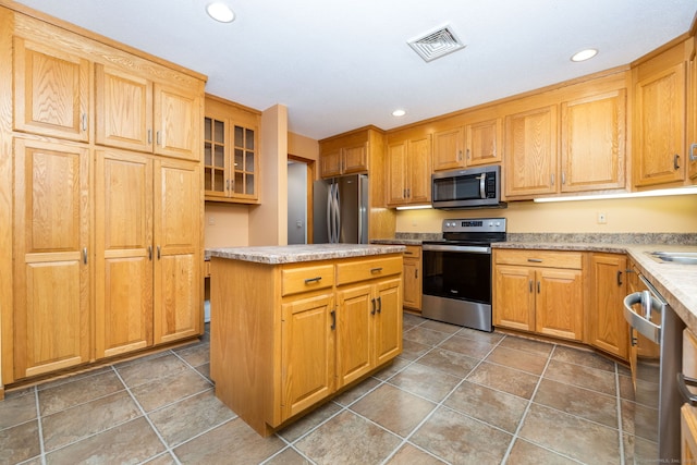 kitchen with visible vents, a center island, glass insert cabinets, recessed lighting, and stainless steel appliances