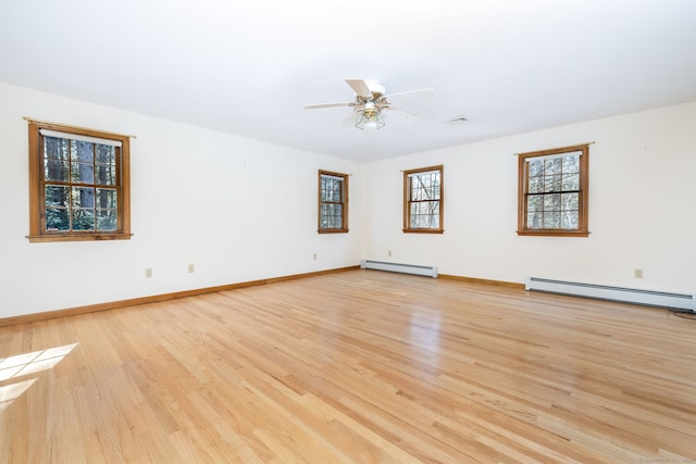 spare room featuring a baseboard radiator, baseboards, baseboard heating, and light wood finished floors