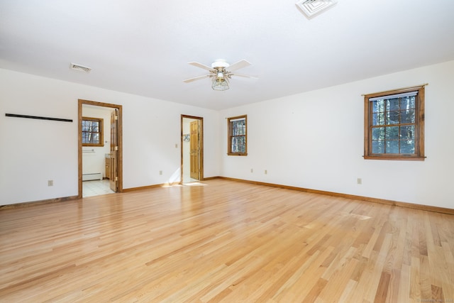 empty room with visible vents, light wood-style flooring, and a baseboard heating unit